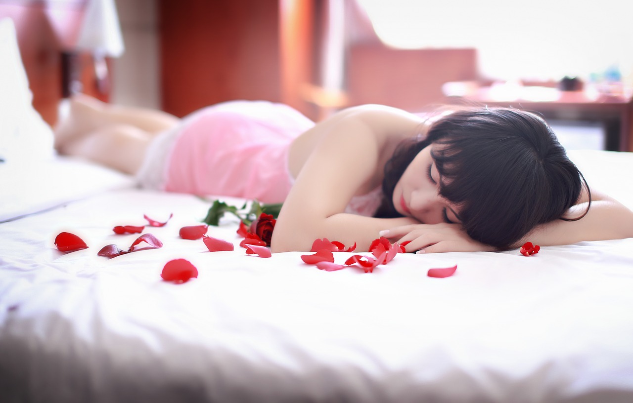 Brünette liegt auf einem mit Rosenblättern bestreuten Bett